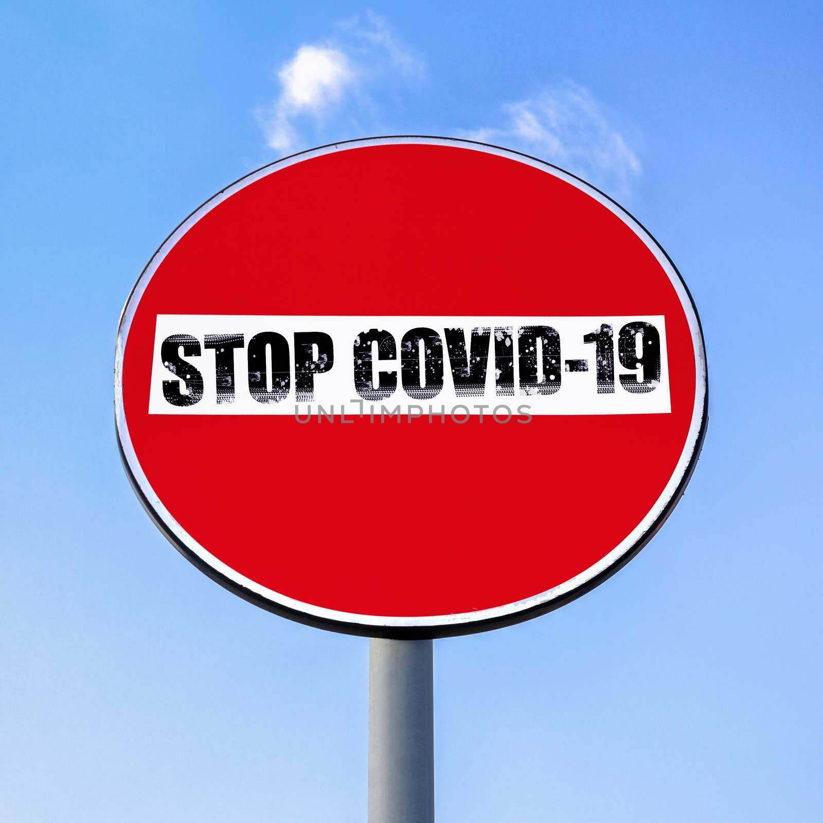No access denied road sign with message STOP COVID-19 on sky background. COVID-19 alert banner. Lockdown. Concept of stop working activities due to coronavirus medical emergency.