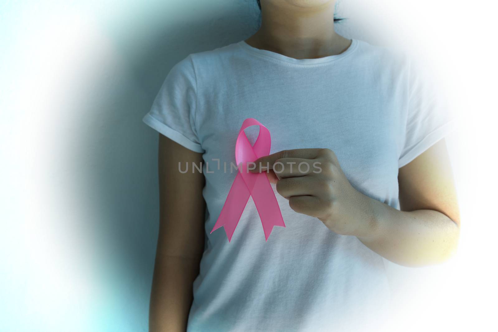 Vintage woman holding a pink ribbon breast cancer awareness Health care and medical concept isolated on pink background.