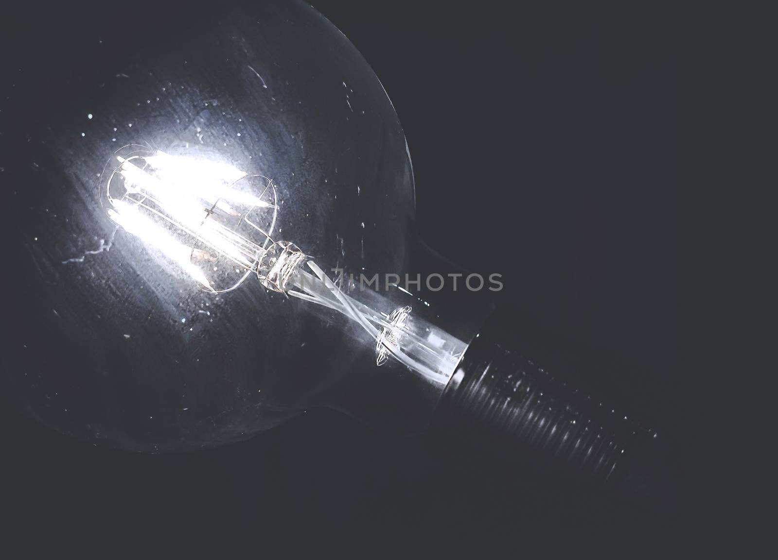 Vintage bulb on the dark background. Ideas and vintage concept. Retro style photo. Copy space.