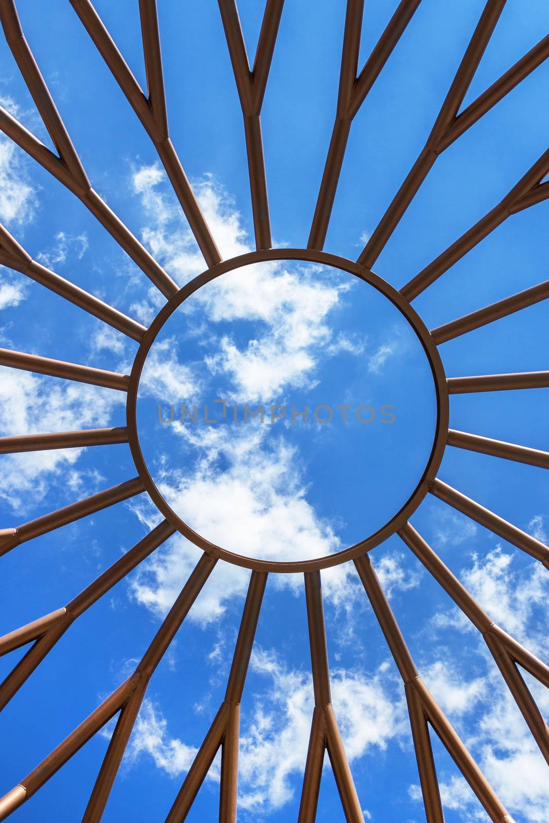 Steel structure architecture detail. Sunny shape with steel rays. Abstract background with nice sky and clouds.
