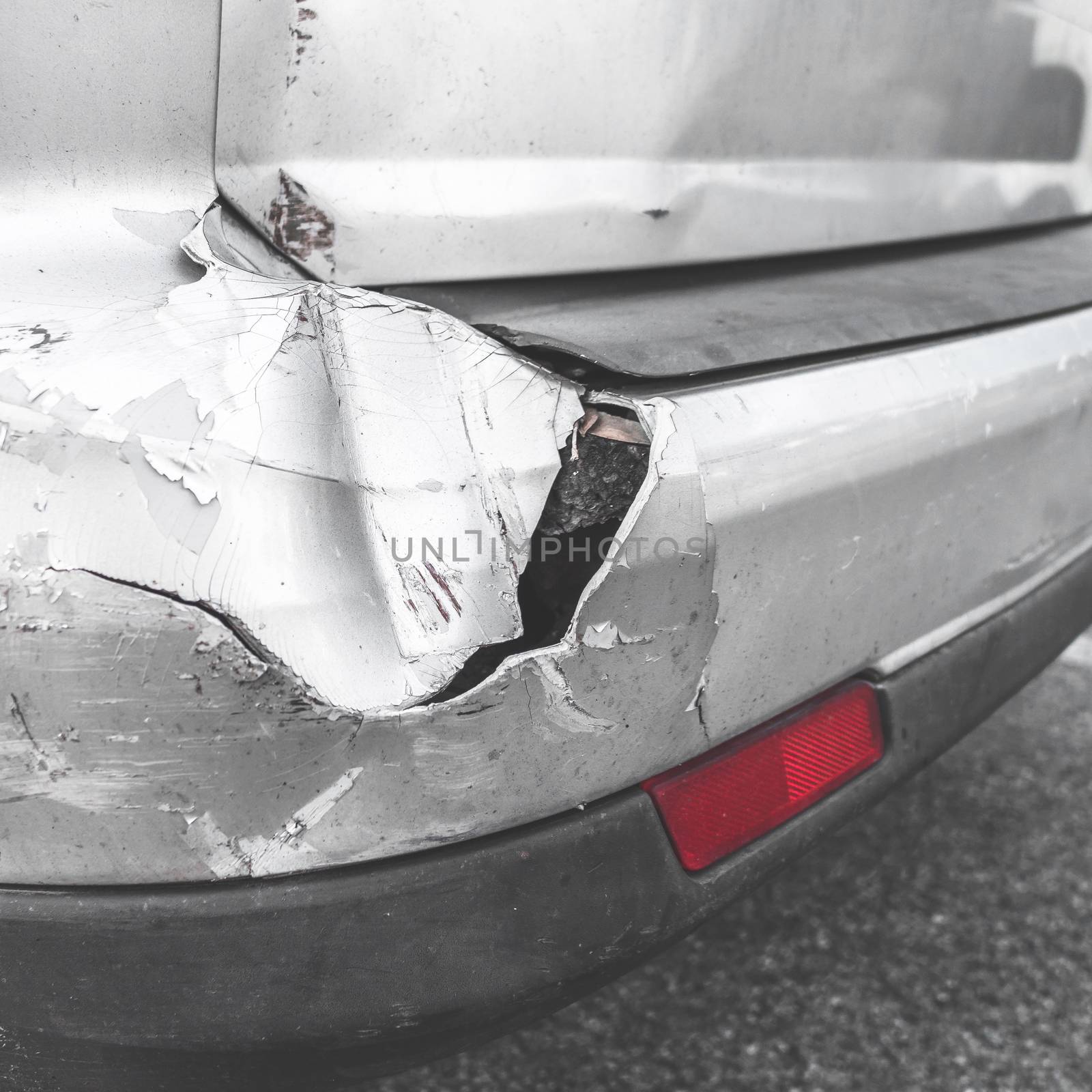 Damaged car. Road accident. Back of gray car get damaged from accident on the road. Vehicle bumper dent broken by car crash. Retro style photo.