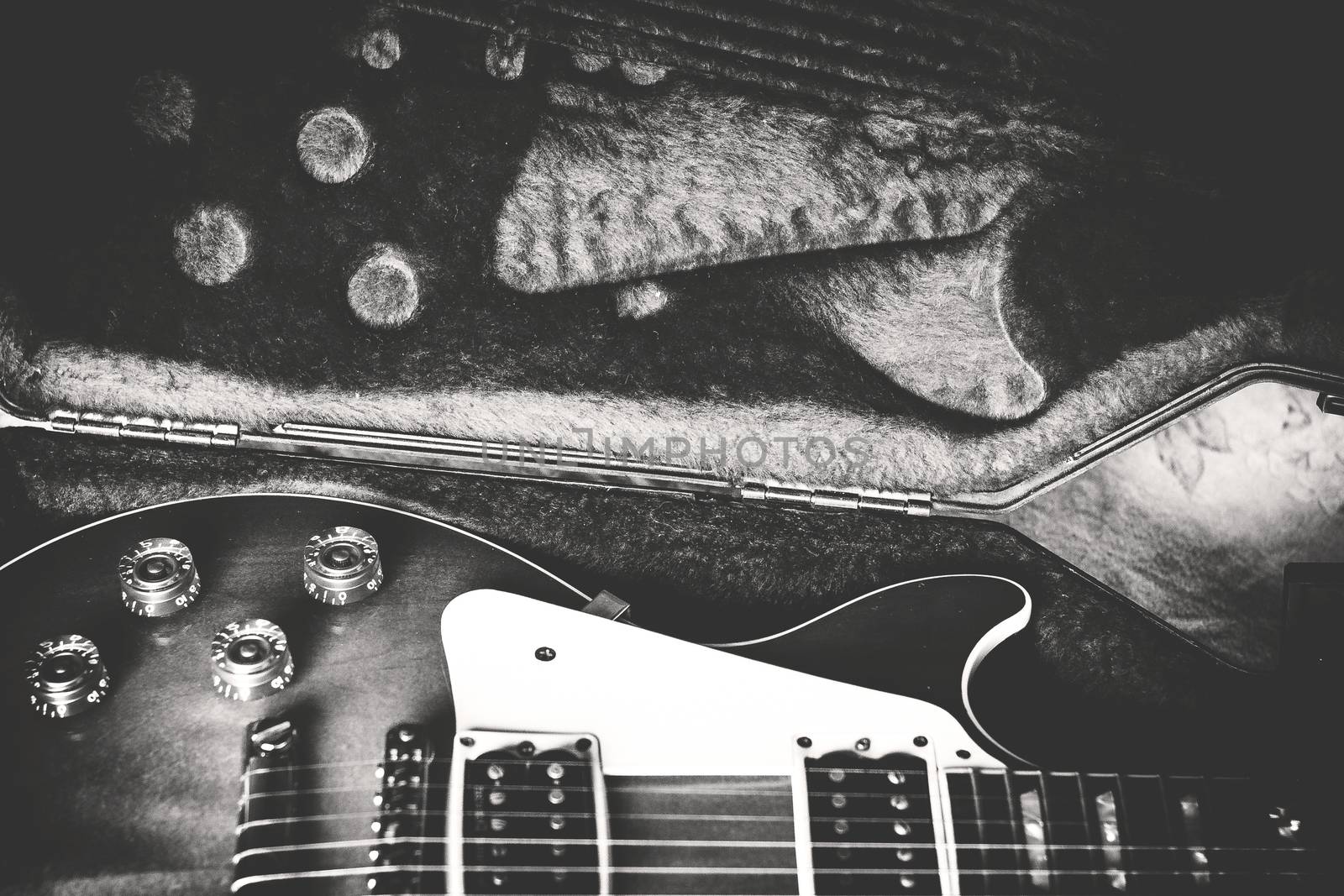 Black and white close-up of an electric guitar laying inside a guitar case. Retro style photo.