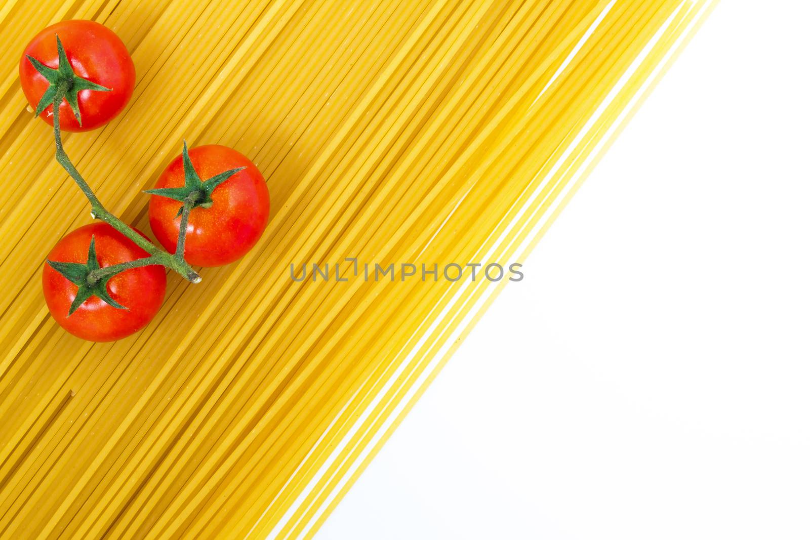 Spaghetti and cherry tomato. Uncooked spaghetti and cherry tomato on white background. Top view with copy space.