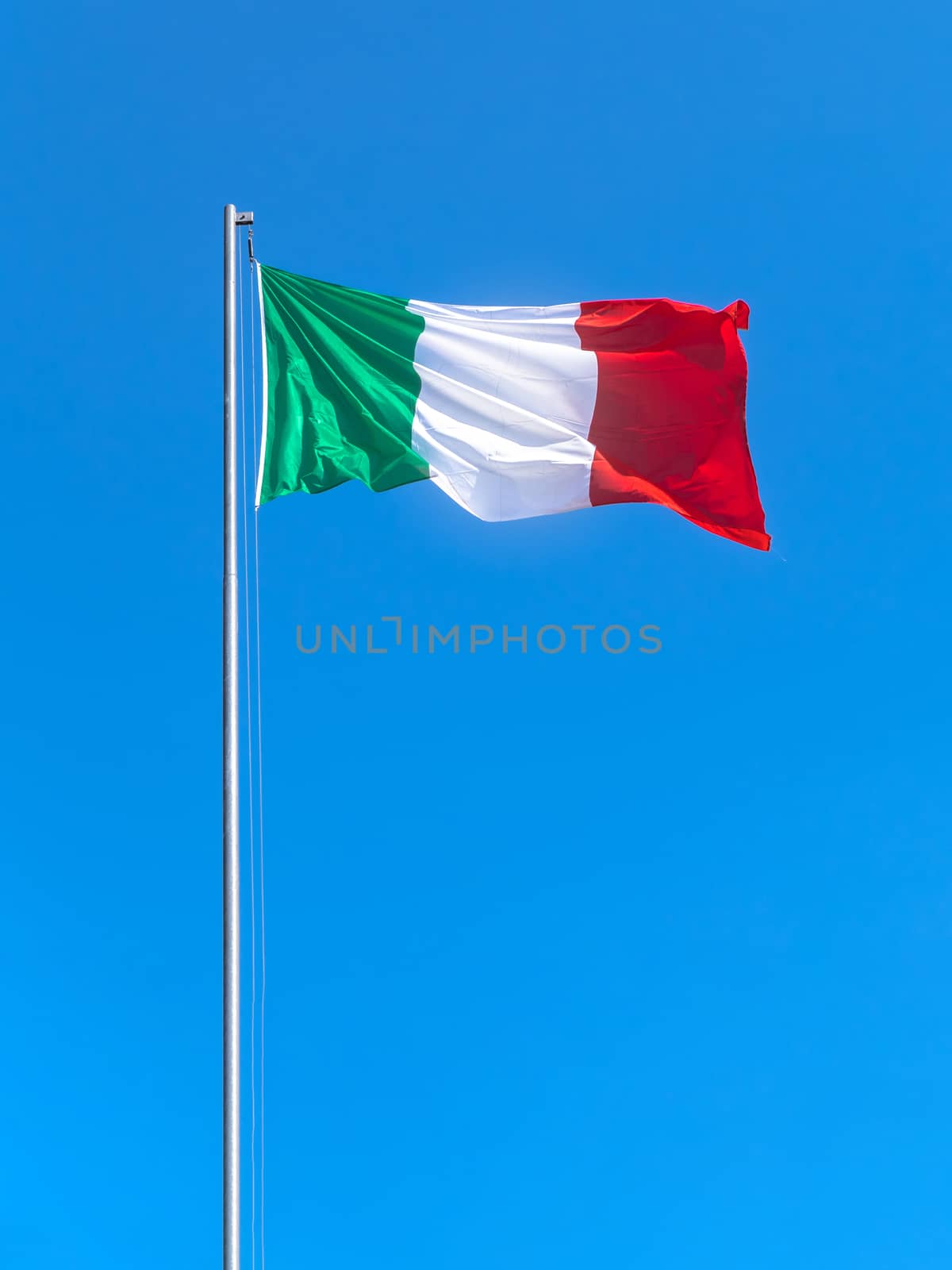 Italy flag waving against a blue sky background. Tricolor flag. Copy Space.