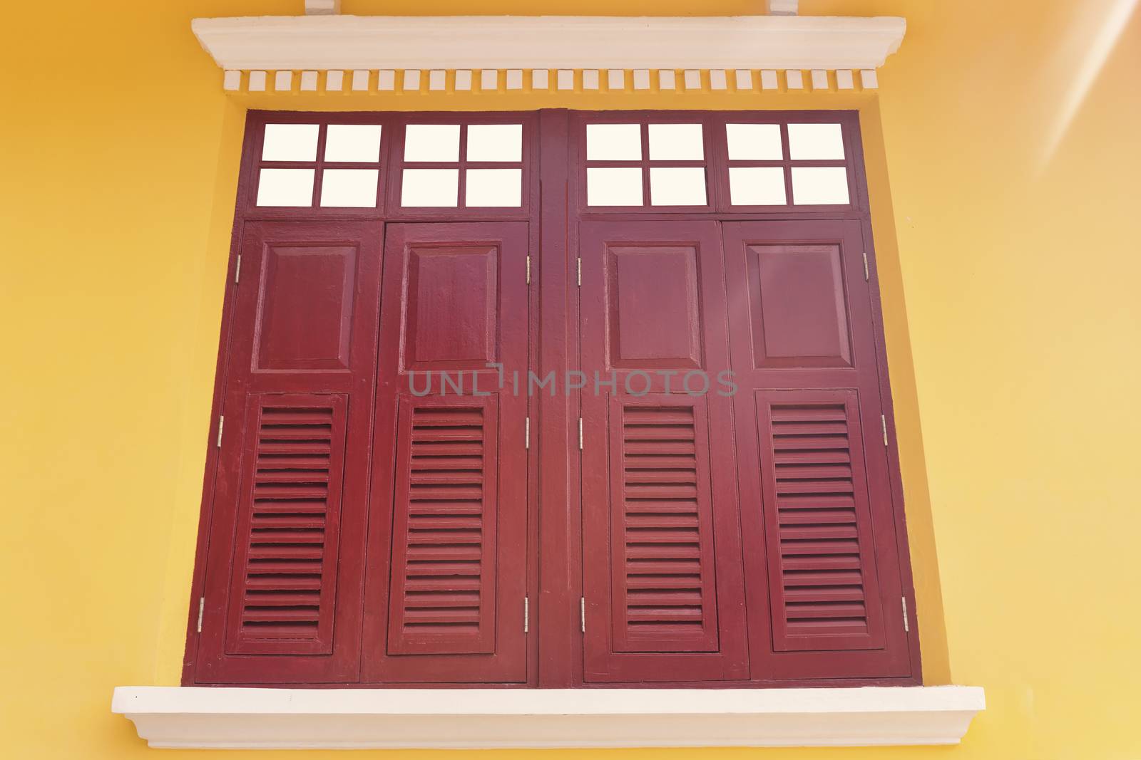Old twin wood windows with yellow wall background. Old style double wood windows.
