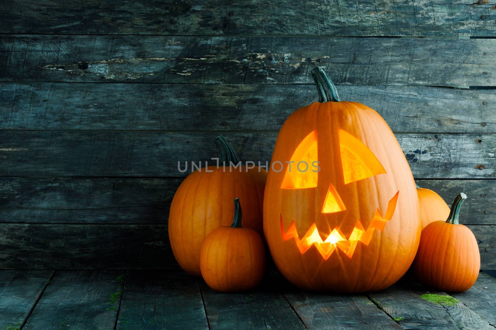 Halloween pumpkin head jack o lantern with candle inside on wooden background