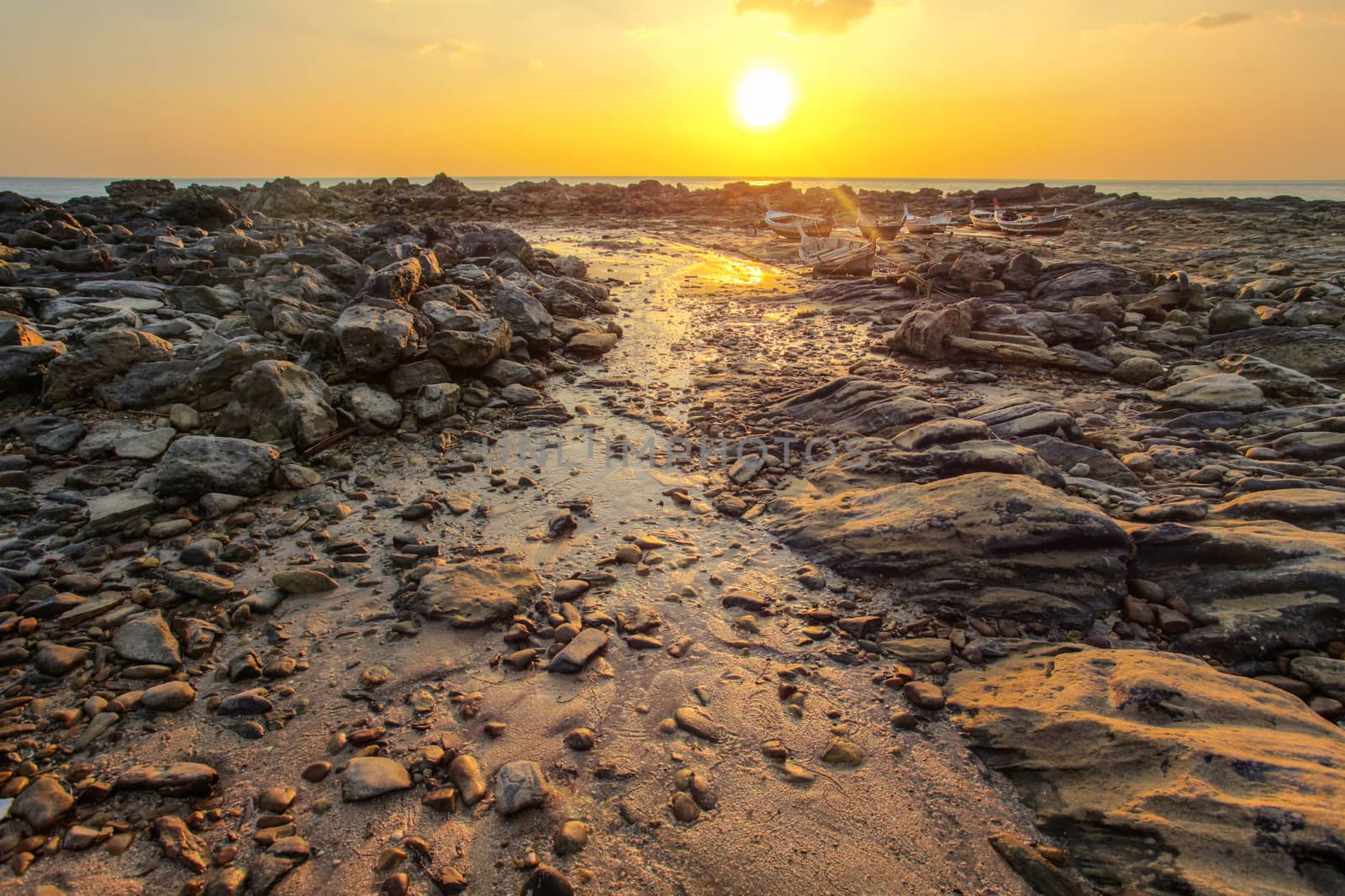 Rocks and beach uncovered in low tide with boats on dry land in  by Ivanko