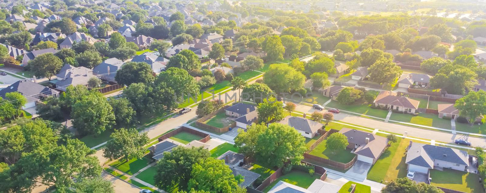 Panoramic Urban sprawl near Dallas, Texas, USA with row of single family houses and large fenced backyard. Aerial view residential neighborhood subdivision surrounded by mature trees