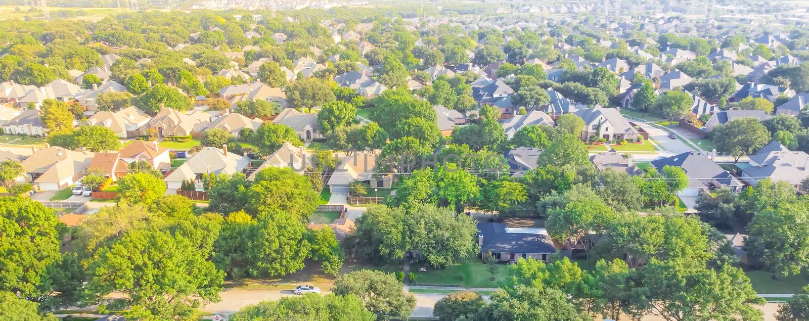 Panoramic Urban sprawl near Dallas, Texas, USA with row of single family houses and large fenced backyard. Aerial view residential neighborhood subdivision surrounded by mature trees