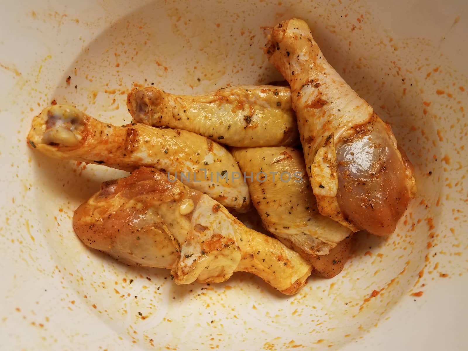 seasoned raw chicken drumsticks in white bowl by stockphotofan1