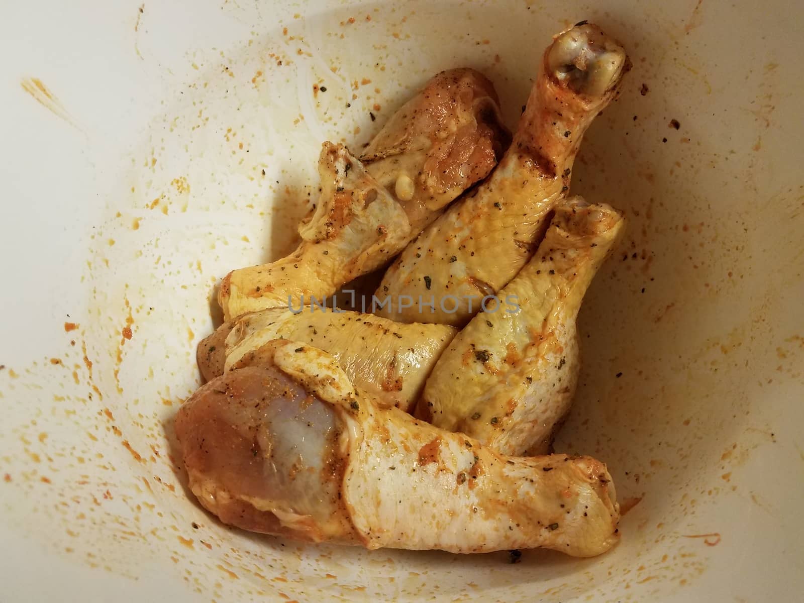 seasoned raw chicken drumsticks in white bowl by stockphotofan1