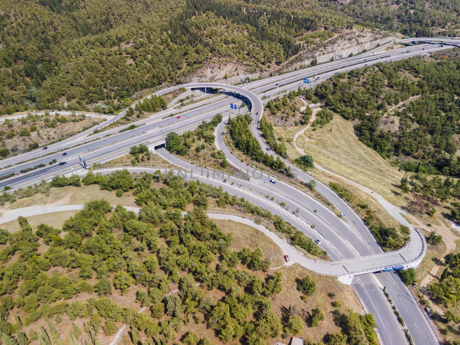 Day top panorama of European multi-level stack highway junction with passing cars through forest.