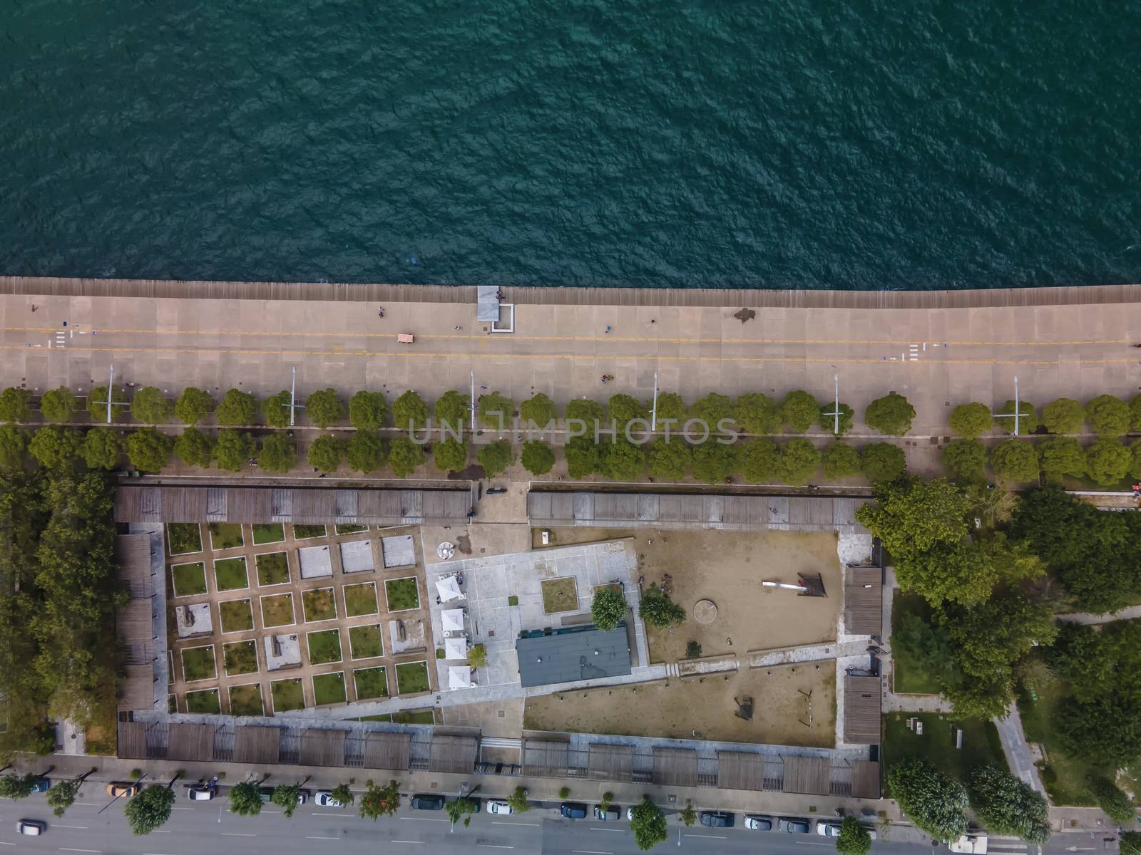 Day top panorama of European city with greenery & pedestrian area promenade before a calm seafront.