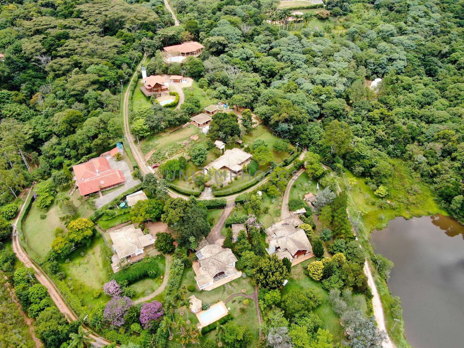 Aerial view of valley with lake, forest and villas in tropical country. Green mountain with forest on Brazil
