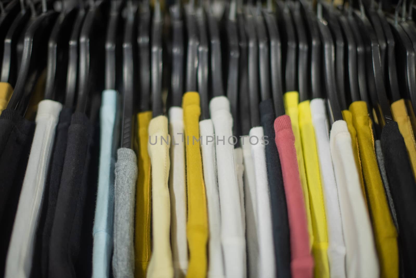 Close up shot of assortment of t shirts on rack by rushay