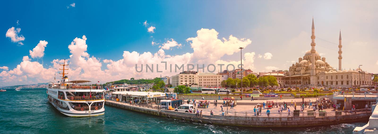 ISTANBUL, TURKEY - JULY 5, 2014: Yeni Cami Ottoman imperial mosque located in the Eminönü quarter of Istanbul, Turkey. Strait of Bosporus with ships in foreground and blue cloudy sky in background.