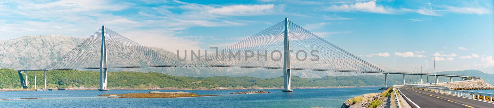 Panorama of bridge and car road in Norway, Europe. Auto travel through scandinavia. Blue cloudy sky, lake and bridge in background.
