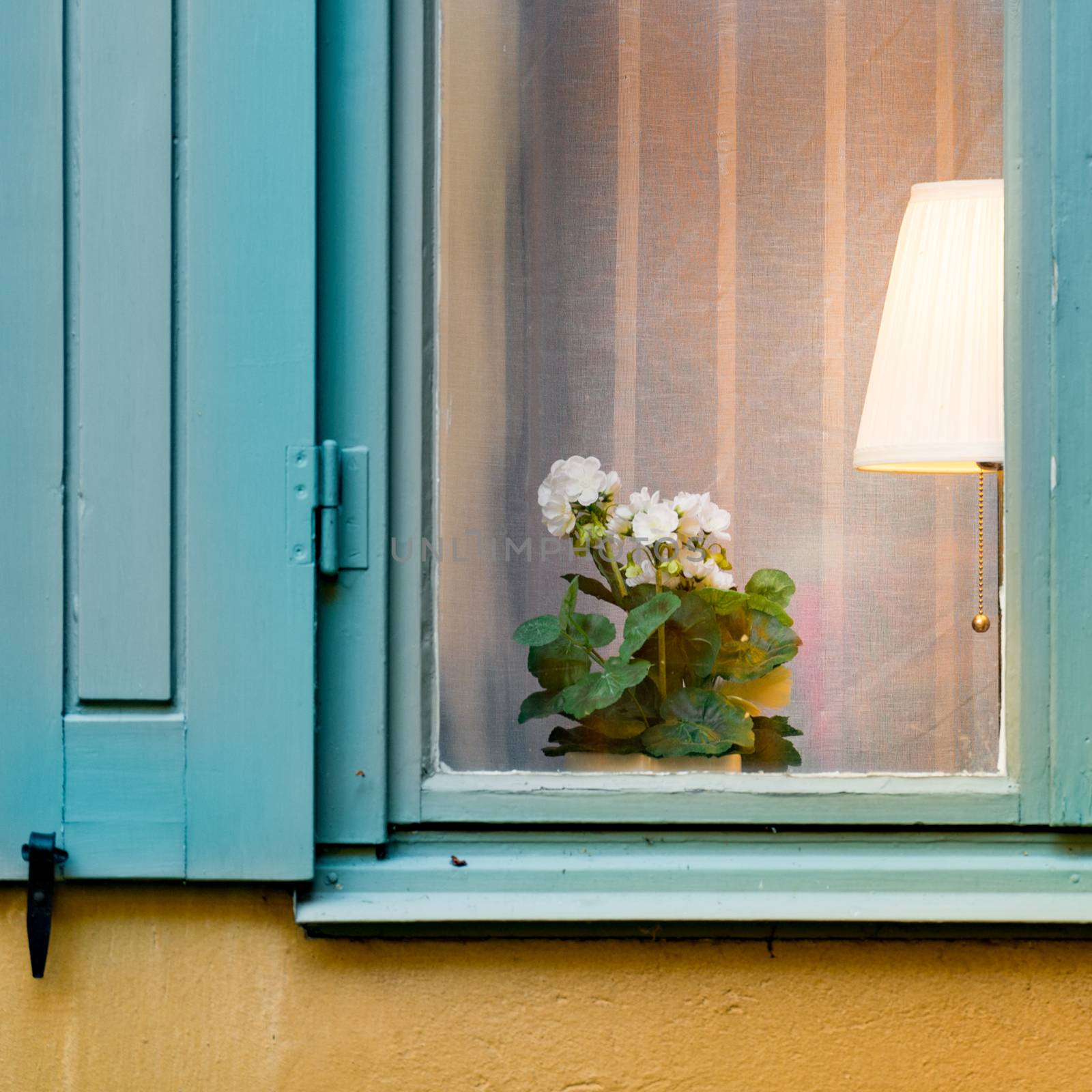 Details of old house window with flower and lamp inside. Yellow wall of building. Stockholm, Sweden, Scandinavia, Europe.