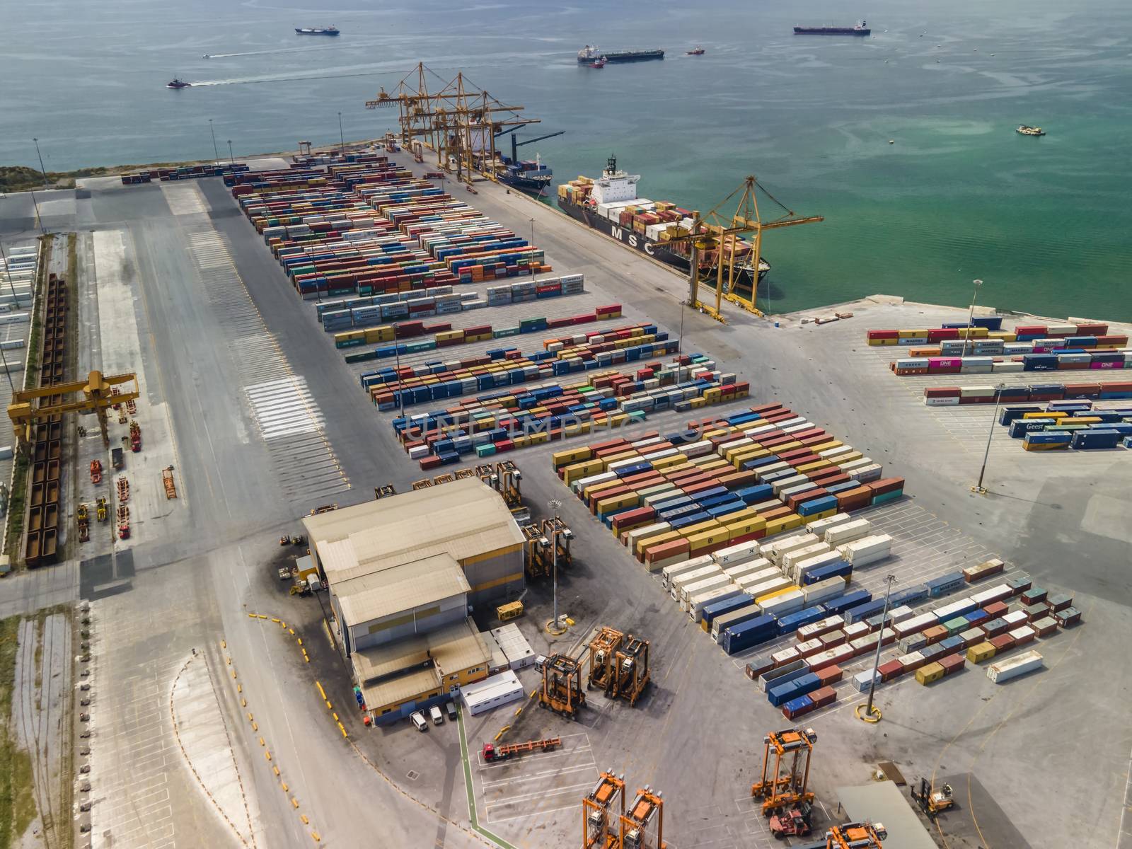 Top panorama of large motorized cranes on sea port, with containers on commercial berthing dock pier.