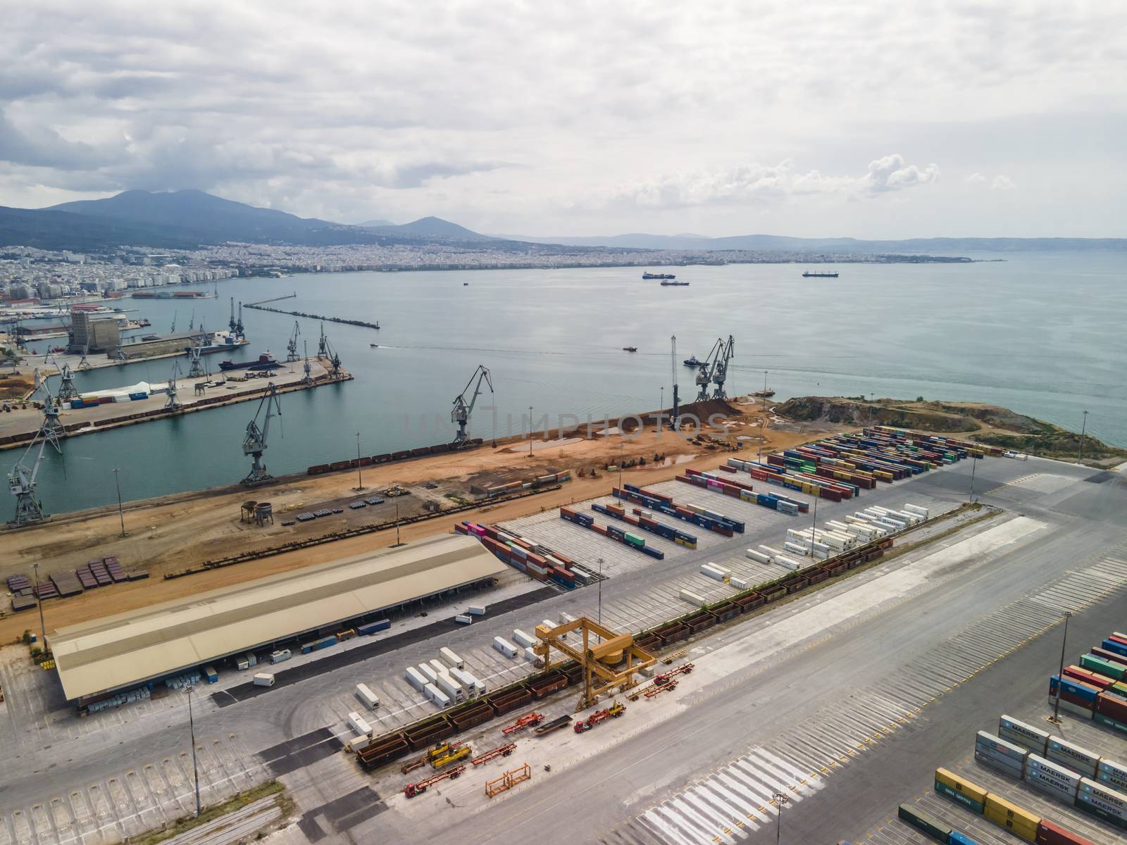 Day top panorama of large motorized cranes on sea port, with cargo containers on commercial berthing dock pier.