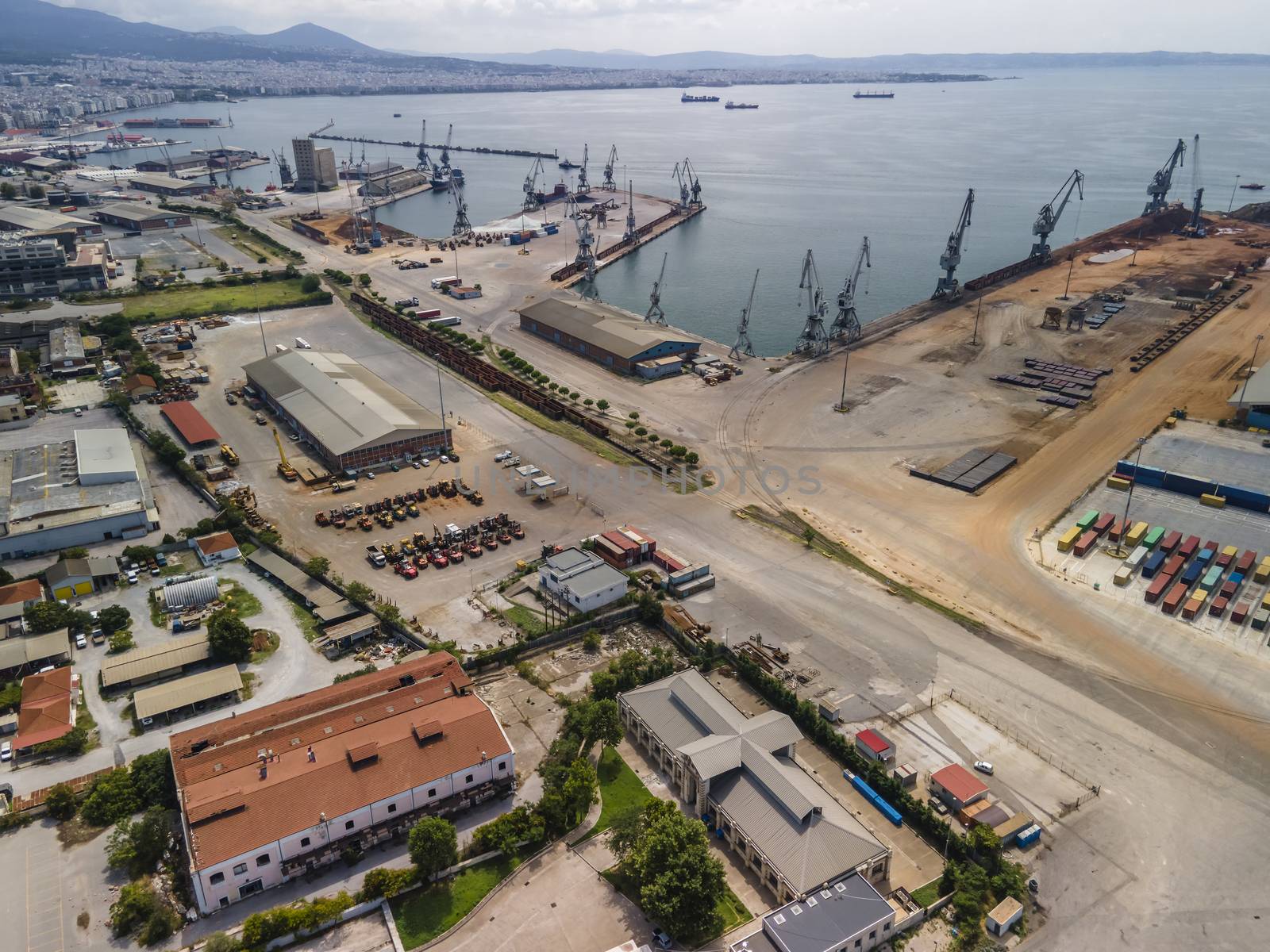 Day top panorama of large motorized cranes on sea port, with cargo containers on commercial berthing dock pier.