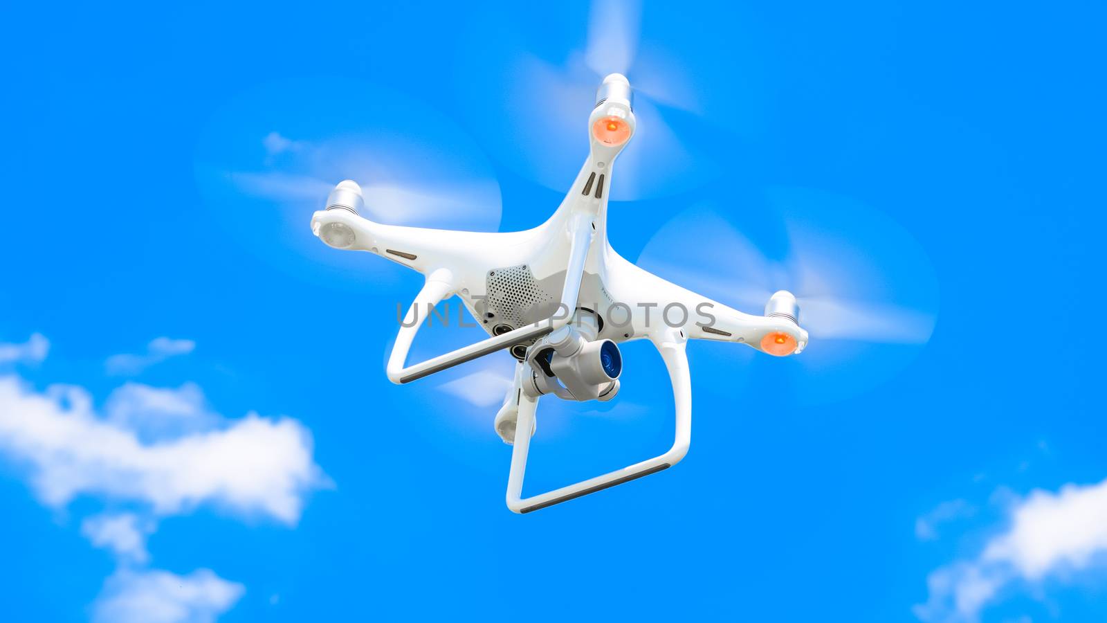 Drone DJI Phantom 4 in flight. Quadrocopter against the blue sky with white clouds. The flight of the copter in the sky.