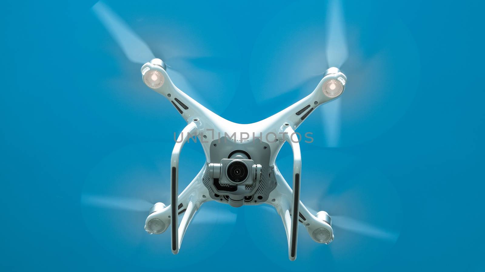 Drone DJI Phantom 4 in flight. Quadrocopter against the blue sky with white clouds. The flight of the copter in the sky.