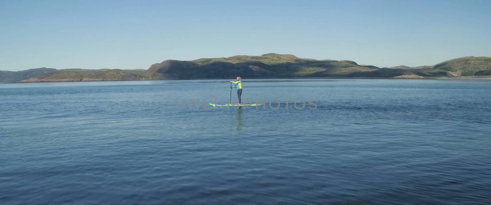 A girl on a boots board is rowing a paddle. Sap surfing.