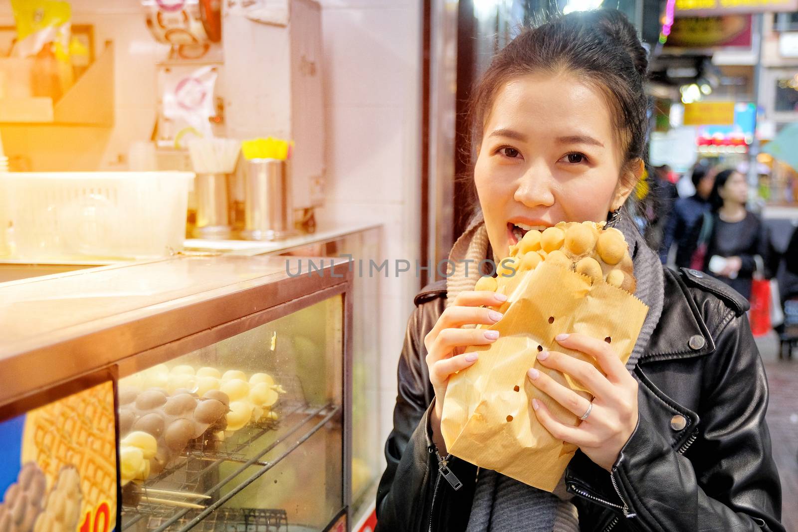 Young woman eating waffle street food in hong kong