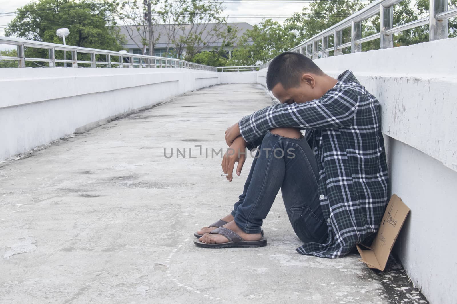 Unhappy homeless man sitting on overpass
