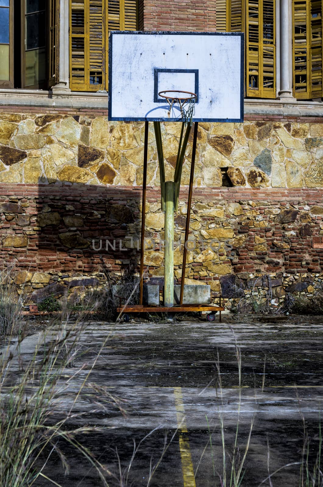 Old basketball hoop is slowly decaying behind old abandoned apartment building.