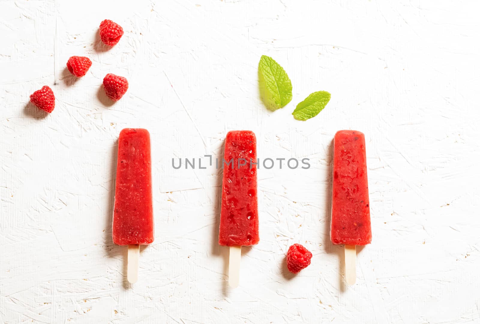 Delicious strawberry popsicles on light background