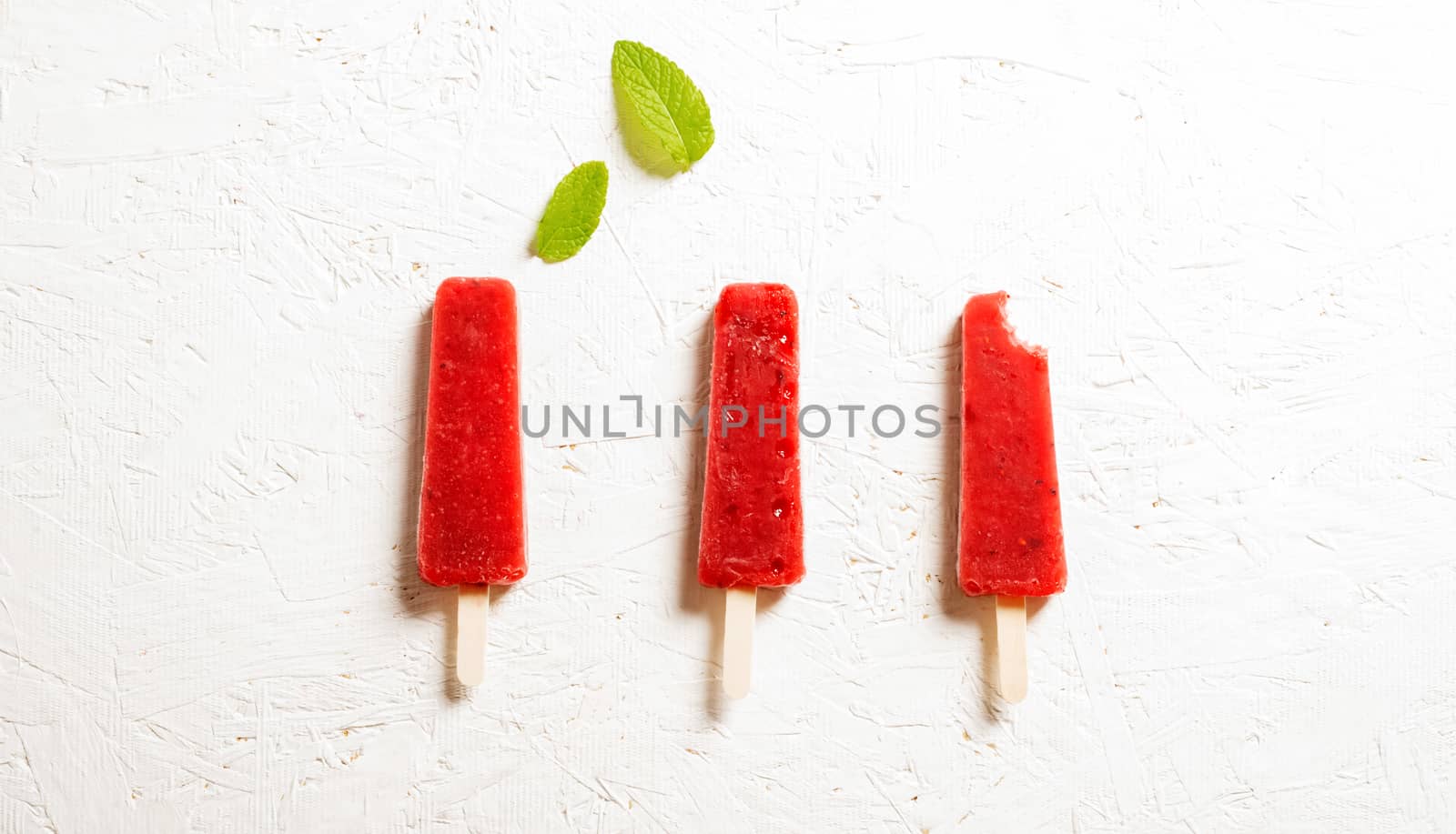 Delicious strawberry popsicles on light background