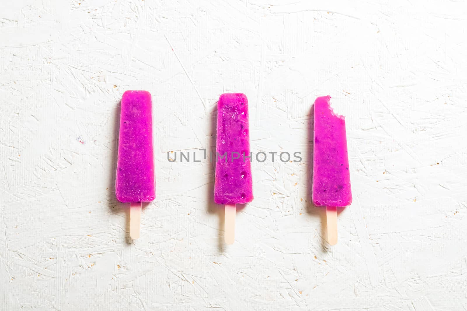 Delicious strawberry popsicles on light background