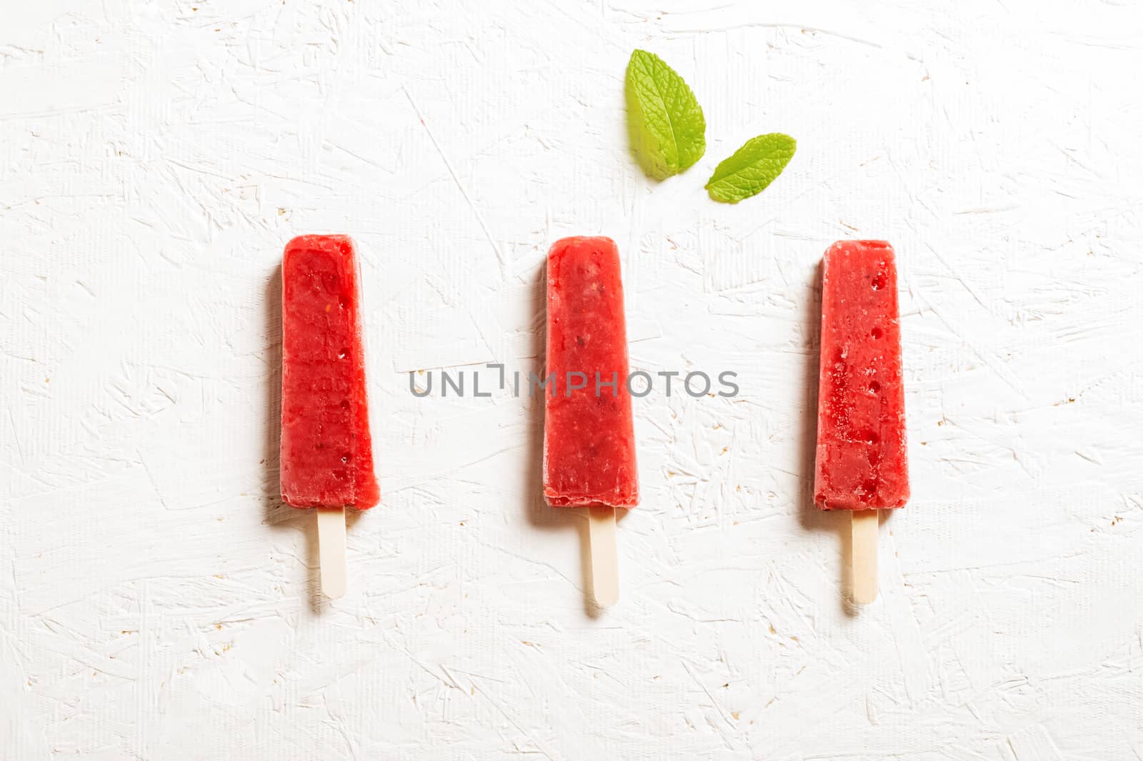 Delicious strawberry popsicles on light background