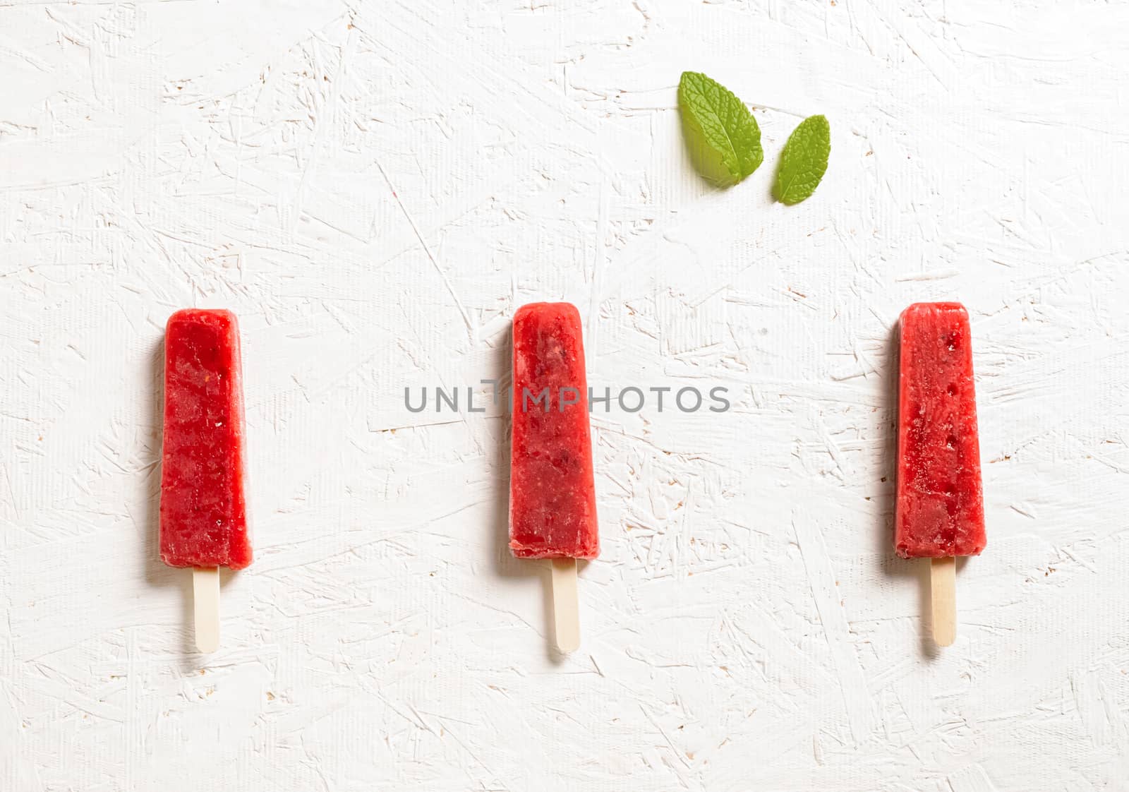 Delicious strawberry popsicles on light background