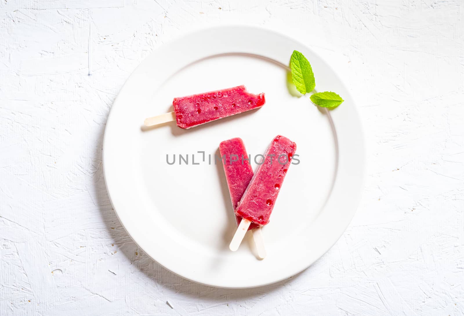 Delicious strawberry popsicles on light background