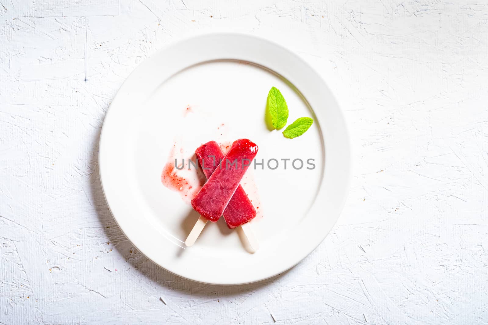 Delicious strawberry popsicles on light background