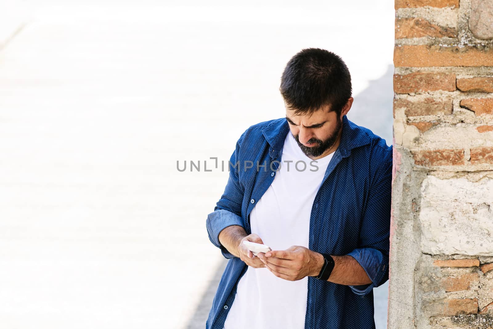 Portrait of a bearded man using his mobile.