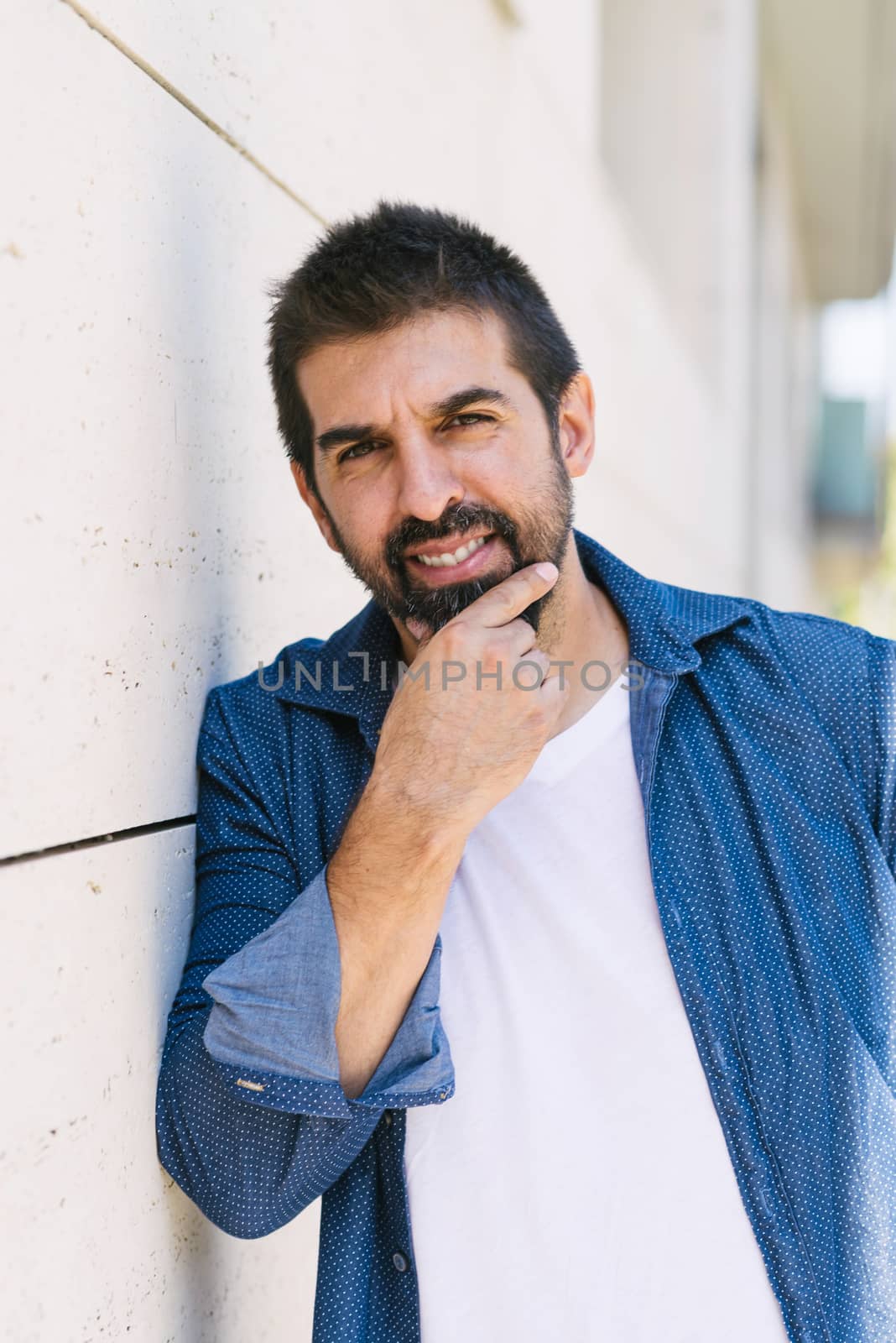 Cheerful bearded male with hand on chin while looking camera