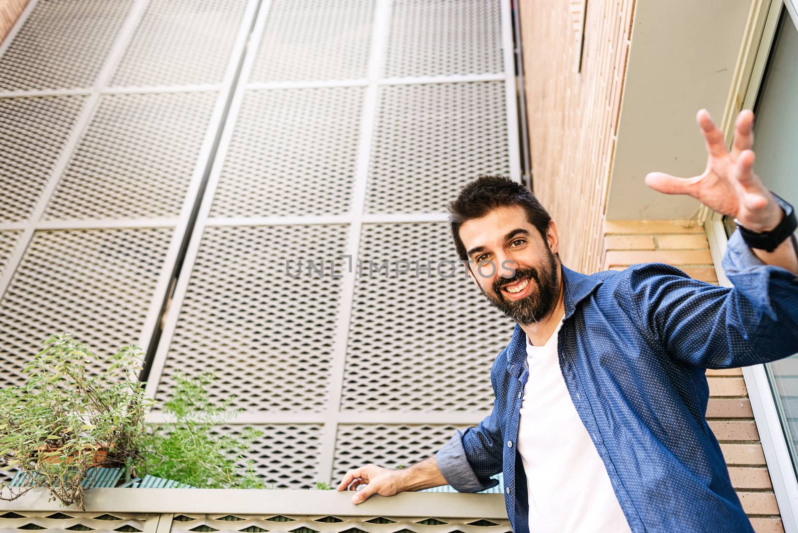 Bearded male with stretched arms looking to camera while smiling