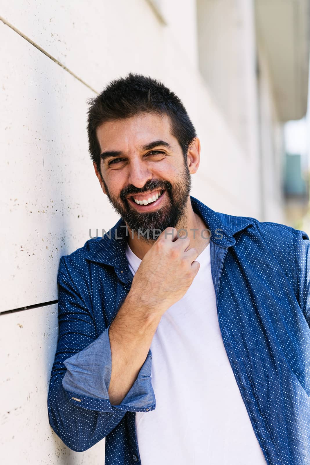 Cheerful bearded male with hand on chin while looking camera