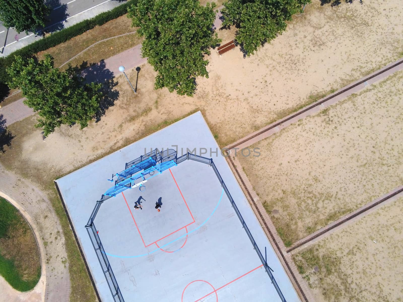 Aerial view of two unrecognizable teen playing basket on a urban court in sunny day