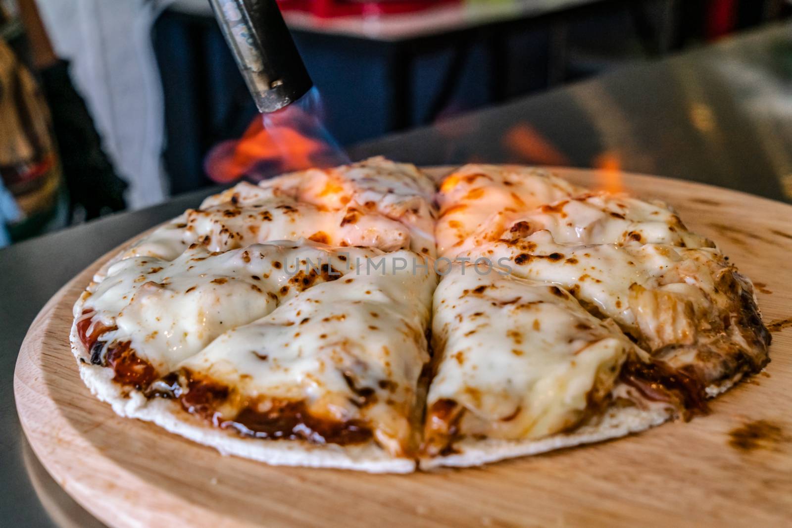 Hand is torch cheese for food at restaurant