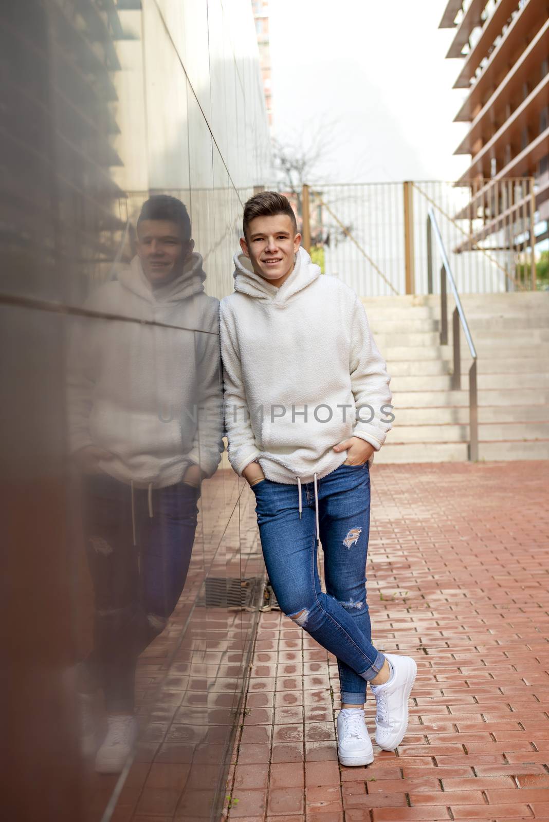 Portrait of young male with hands on pocket leaning on wall outdoors