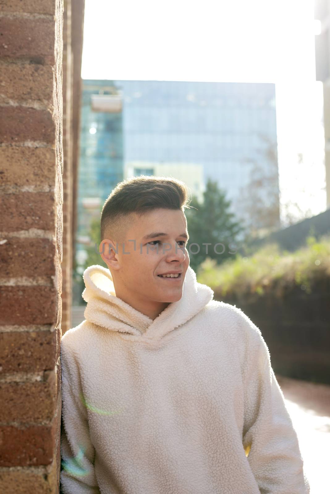 Portrait of young male with hands on pocket leaning on wall outdoors