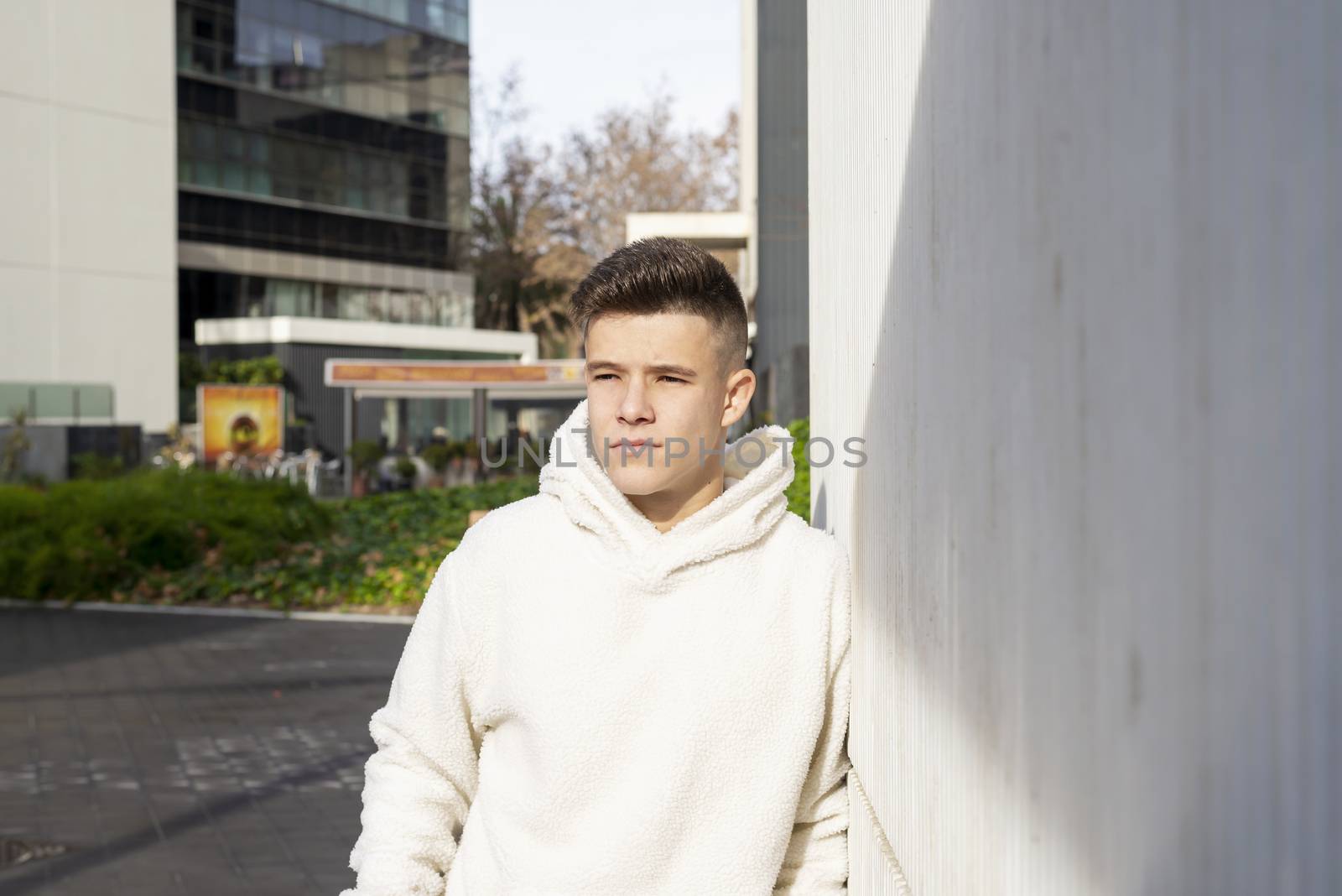 Portrait of young male with hands on pocket leaning on wall outdoors