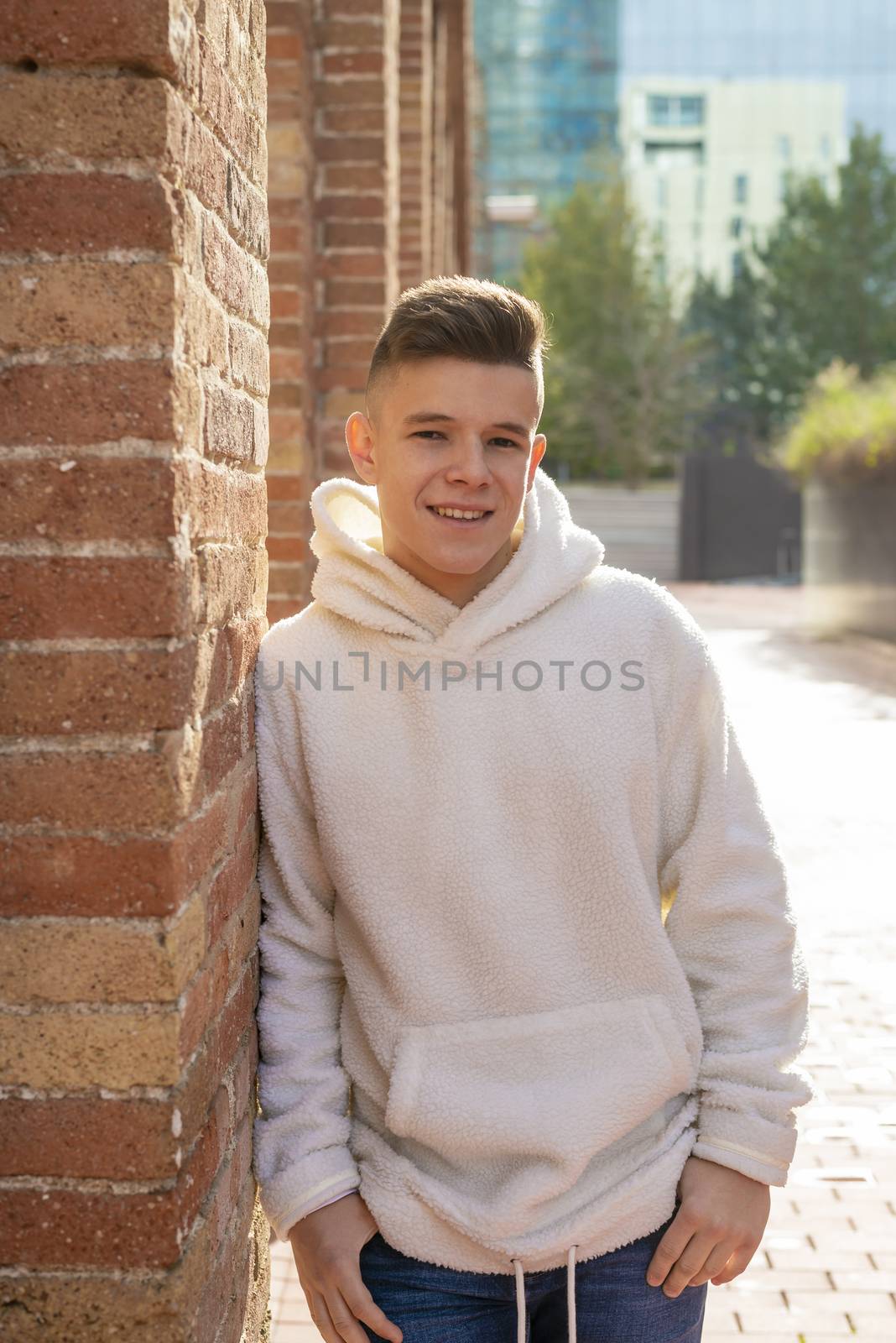 Portrait of young male with hands on pocket leaning on wall outdoors