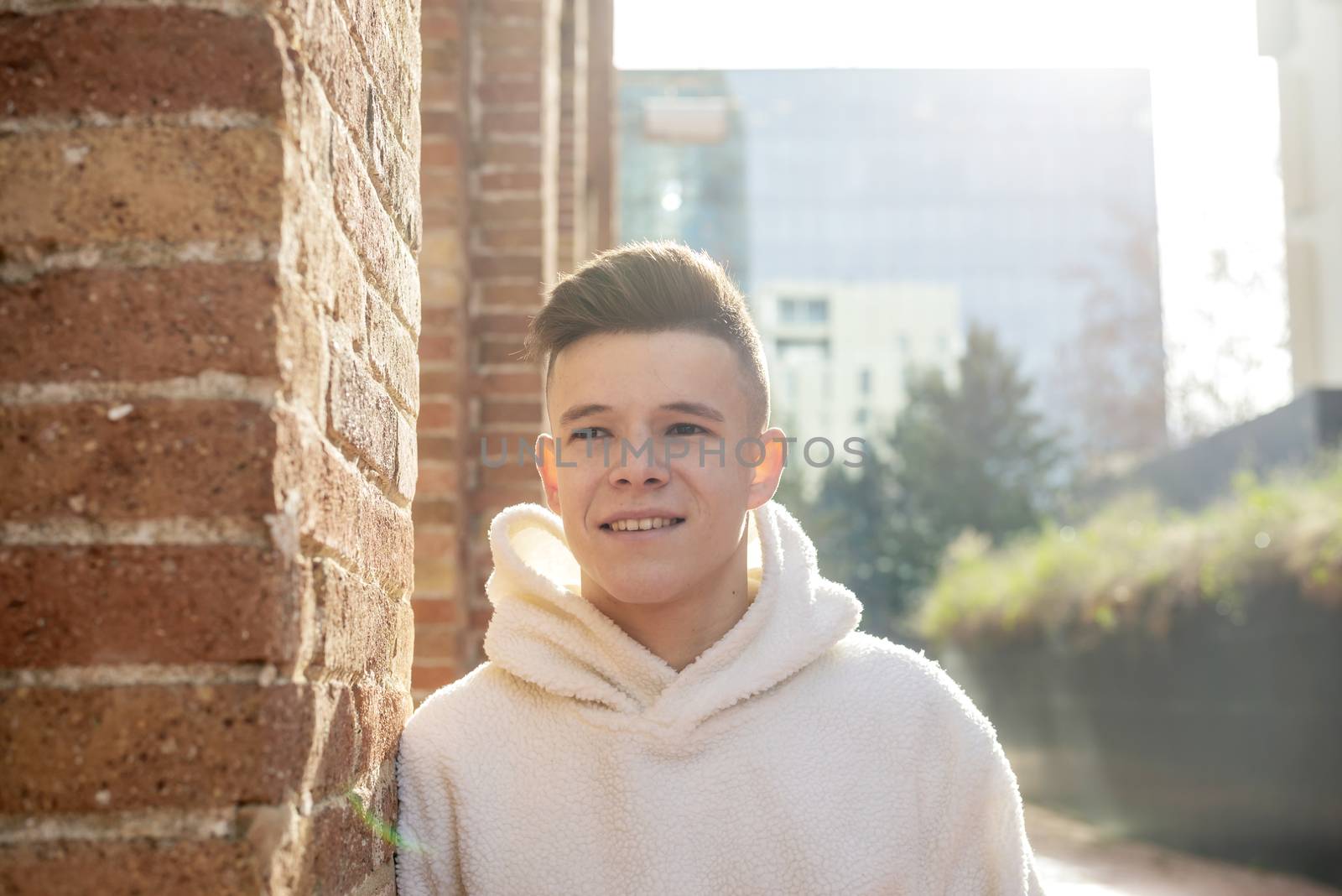 Portrait of young male with hands on pocket leaning on wall outdoors