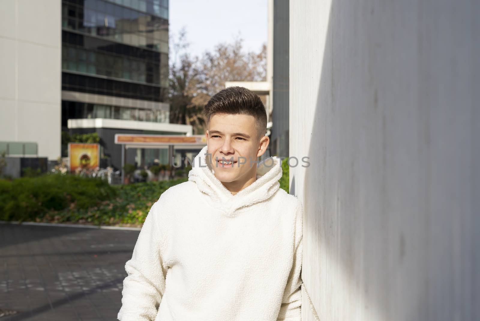 Portrait of young male with hands on pocket leaning on wall outdoors